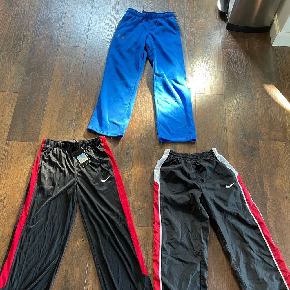 THREE pairs boys size medium Nike and Under Armour pants.